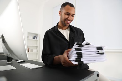 Photo of Happy man with documents at grey table in office