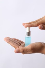 Photo of Woman with bottle of cosmetic serum on white background, closeup