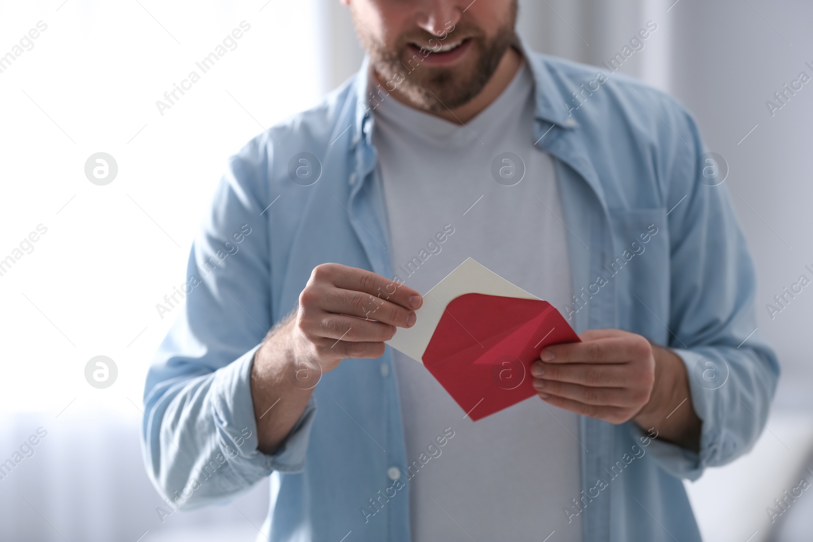 Photo of Man holding envelope with greeting card indoors, closeup