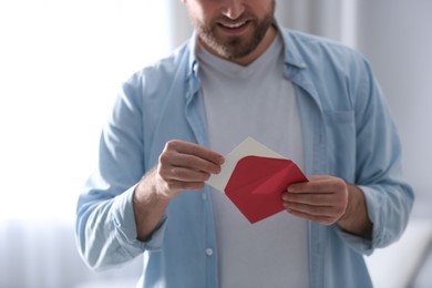 Photo of Man holding envelope with greeting card indoors, closeup