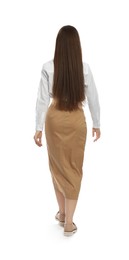 Young woman in casual outfit walking on white background, back view