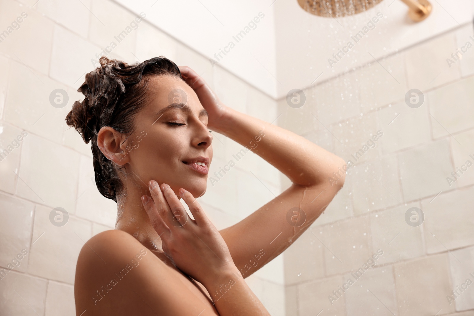 Photo of Young woman washing hair while taking shower at home
