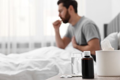 Photo of Sick man coughing on bed at home, selective focus. Space for text