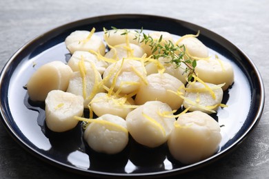 Photo of Raw scallops with thyme and lemon zest on grey table, closeup