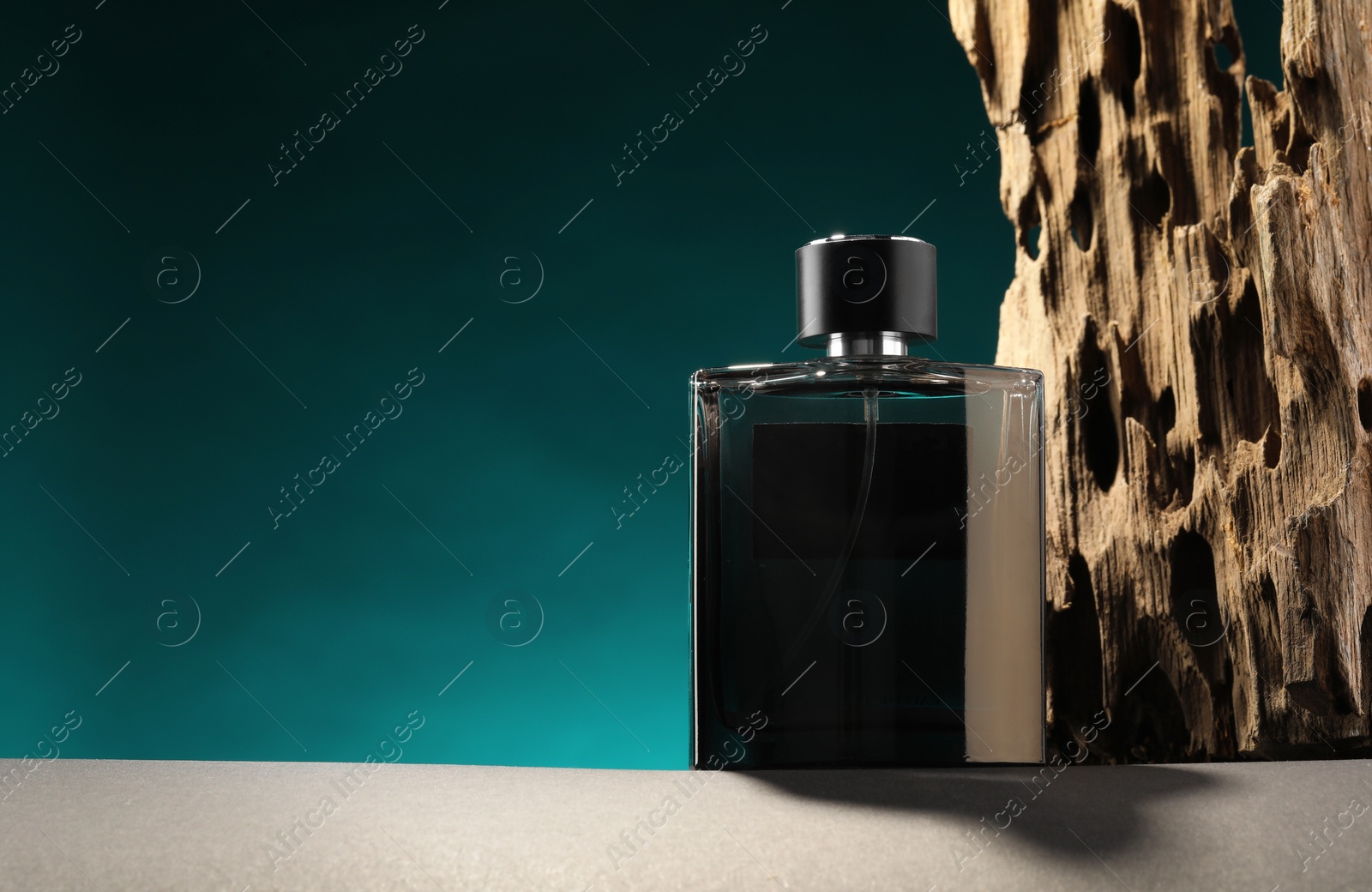 Photo of Luxury men`s perfume in bottle on grey table against color background, space for text