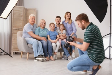 Photo of Professional photographer taking photo of family on sofa in studio