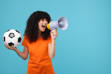 Happy fan with soccer ball using megaphone on light blue background, space for text