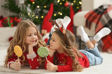 Photo of Cute little girls with lollipops at home. Christmas atmosphere