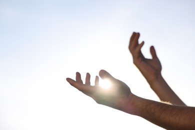 Photo of Feeling freedom. Man reaching for sky on sunny day, closeup of hands