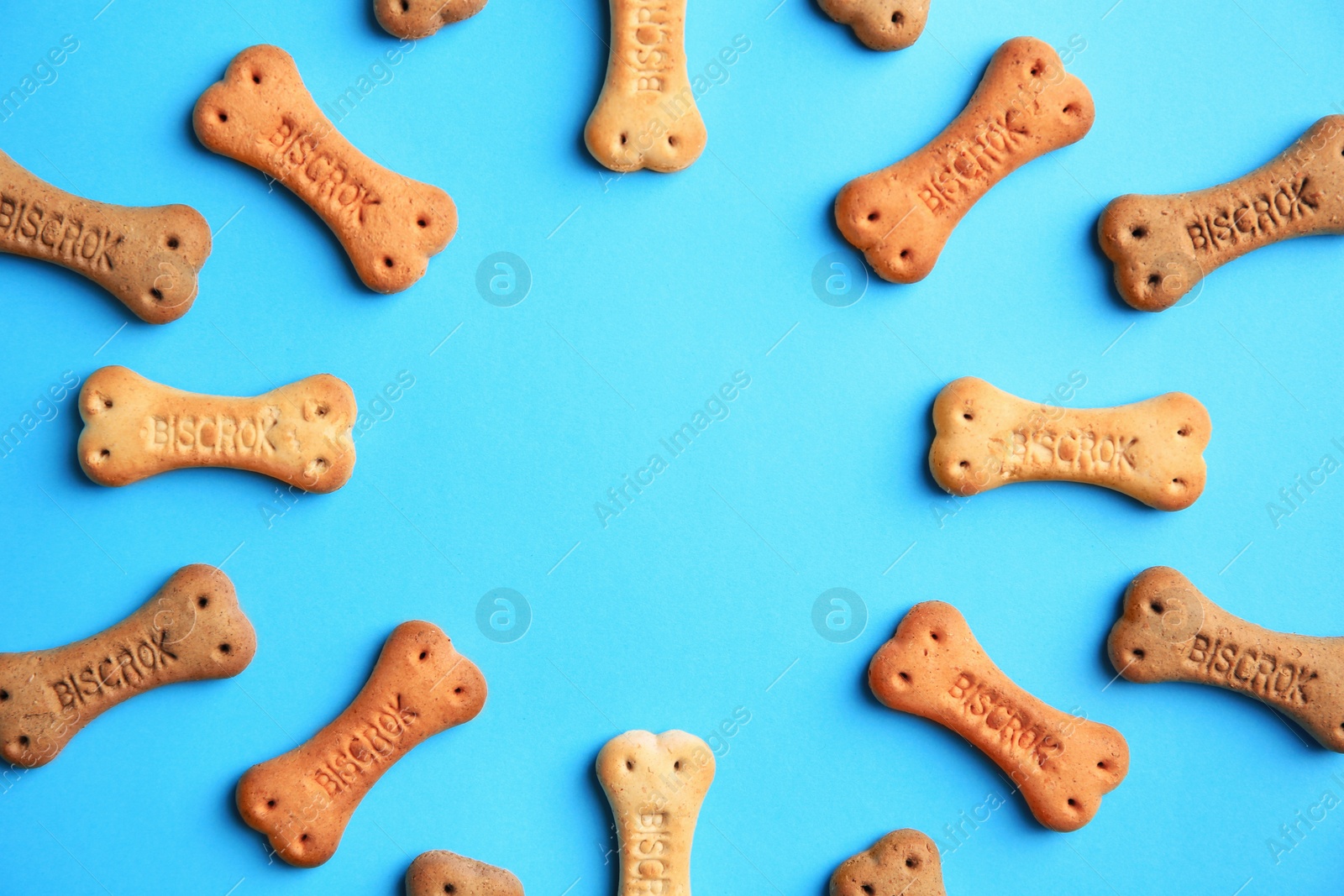 Photo of Frame with bone shaped dog cookies on light blue background, flat lay. Space for text