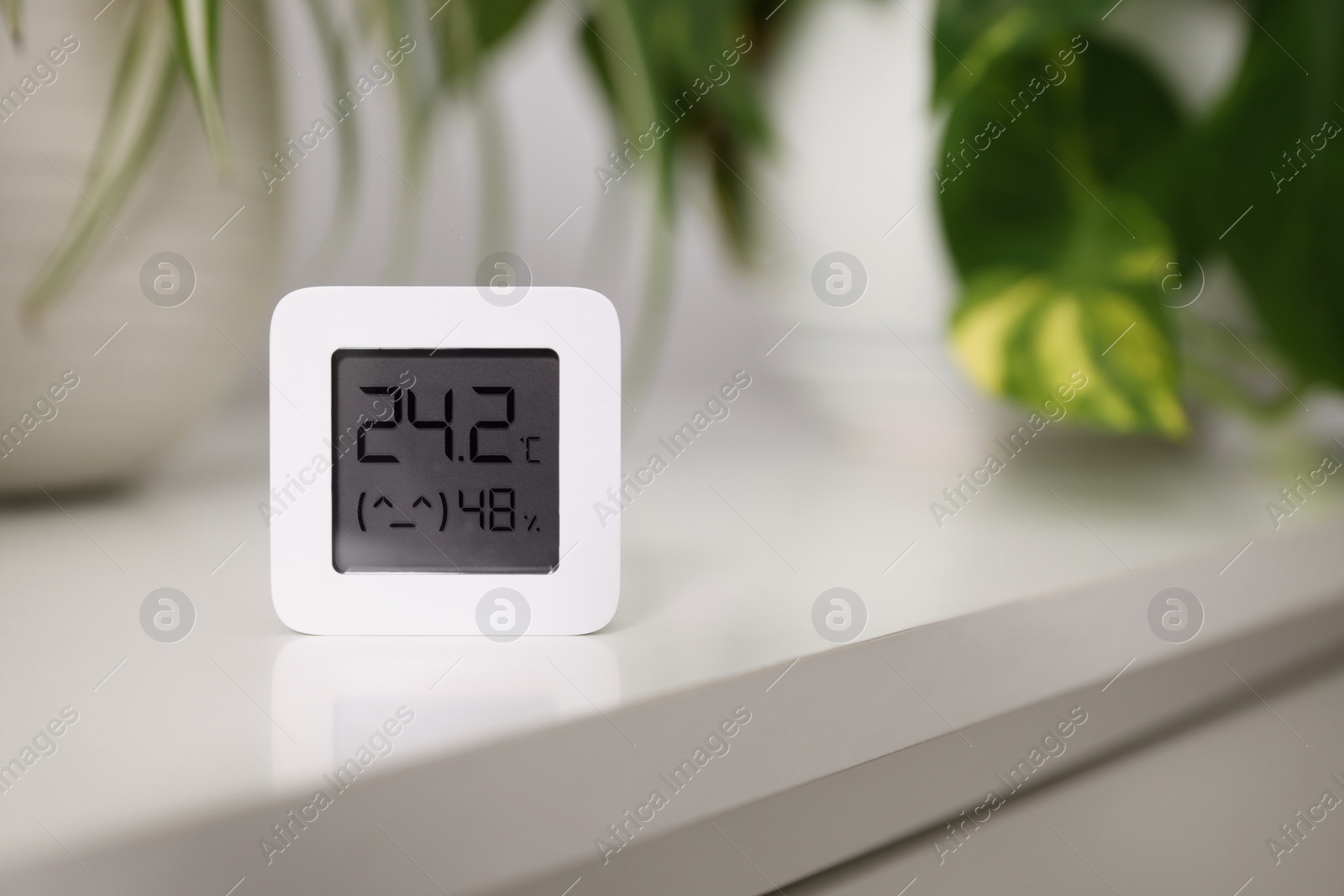 Photo of Digital hygrometer with thermometer on white table, space for text