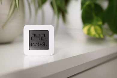 Photo of Digital hygrometer with thermometer on white table, space for text