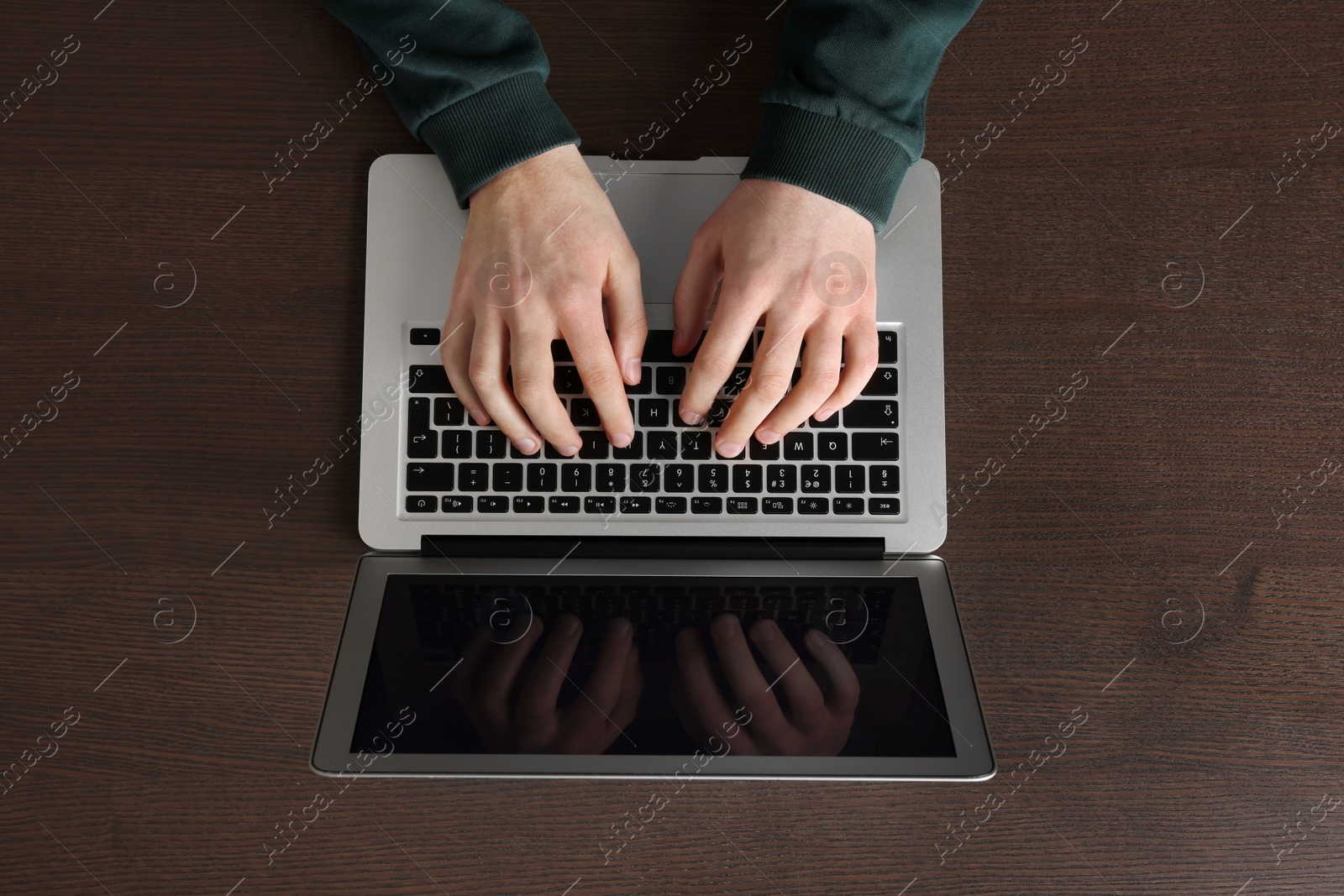 Photo of Man working with laptop at wooden table, top view