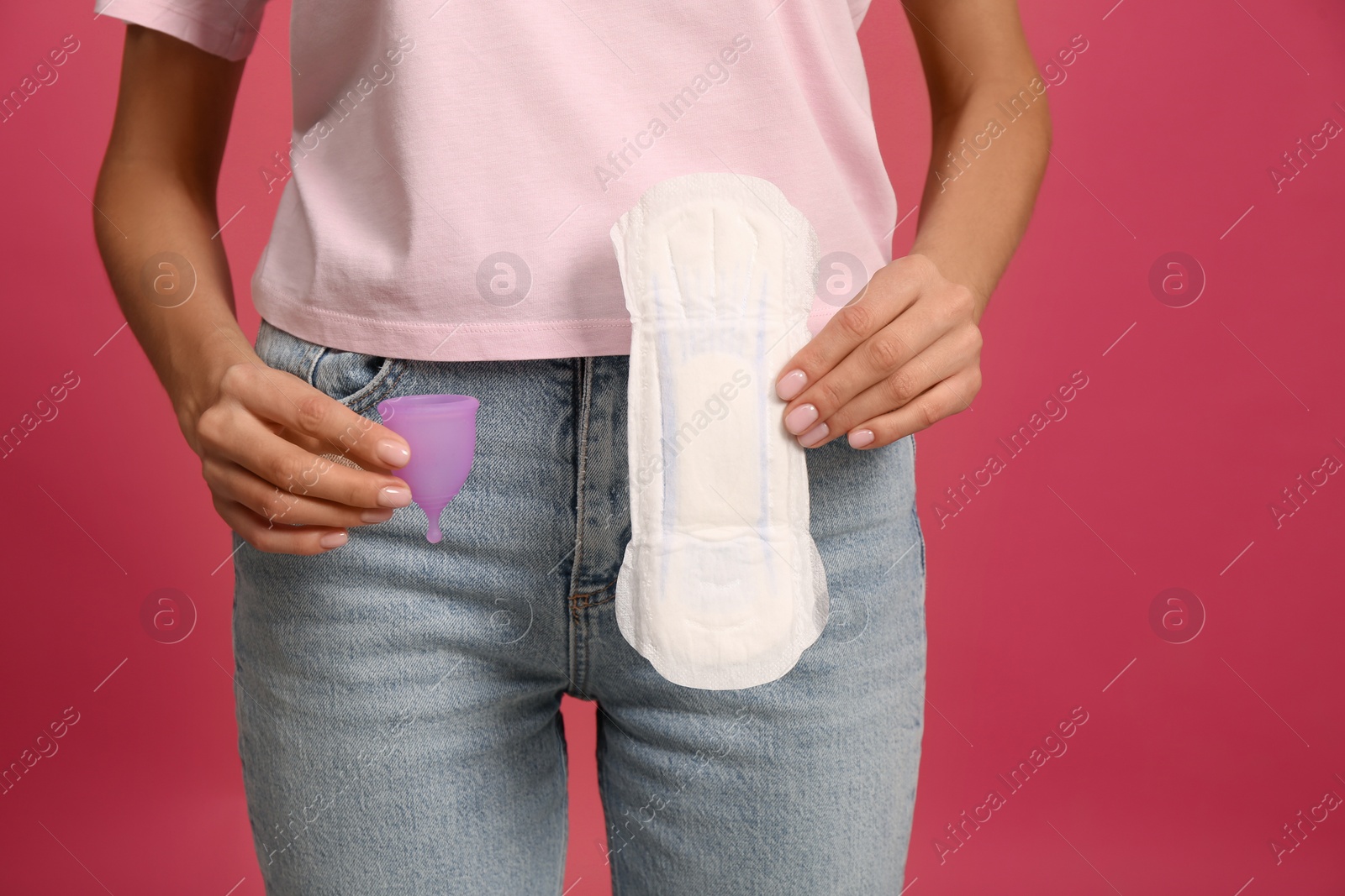 Photo of Young woman with menstrual cup and pad on bright pink background, closeup