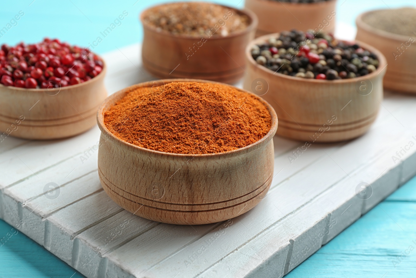 Photo of Bowls with different kinds of pepper on white wooden board