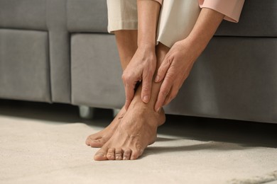 Photo of Mature woman suffering from pain in leg indoors, closeup. Rheumatism symptom