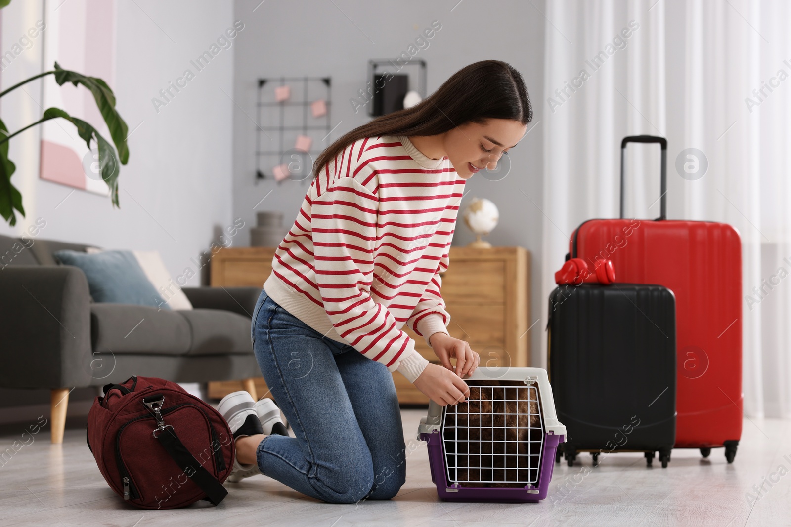 Photo of Smiling woman closing carrier with her pet before travelling indoors