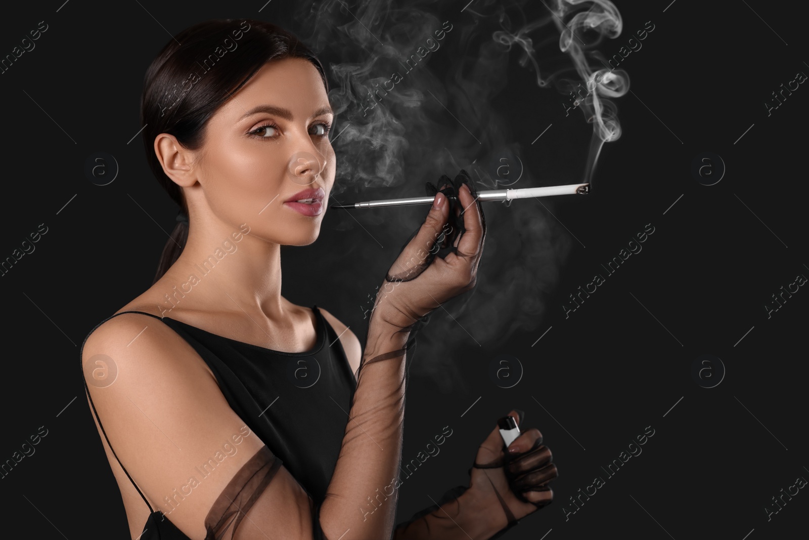 Photo of Woman using long cigarette holder for smoking on black background, space for text