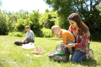 Photo of Mother and her children with plastic bags collecting garbage in park