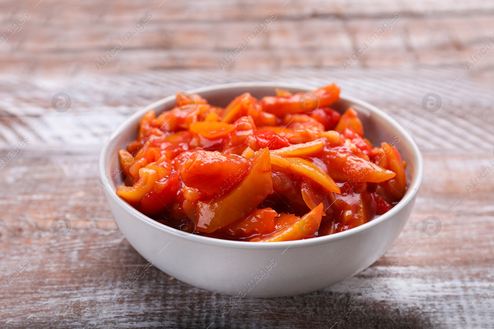 Photo of Bowl of delicious lecho on wooden table, closeup