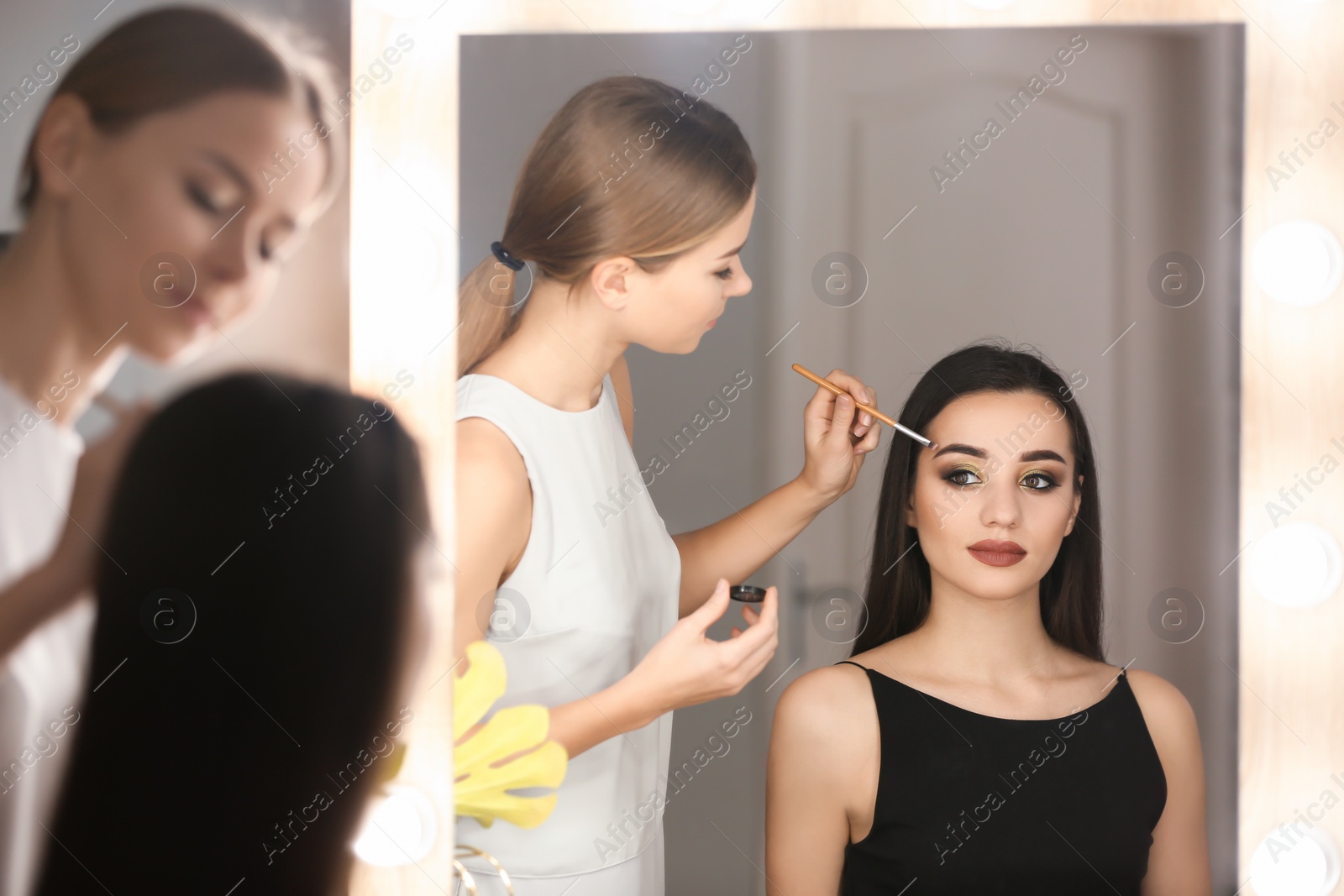 Photo of Professional visage artist applying makeup on woman's face in salon