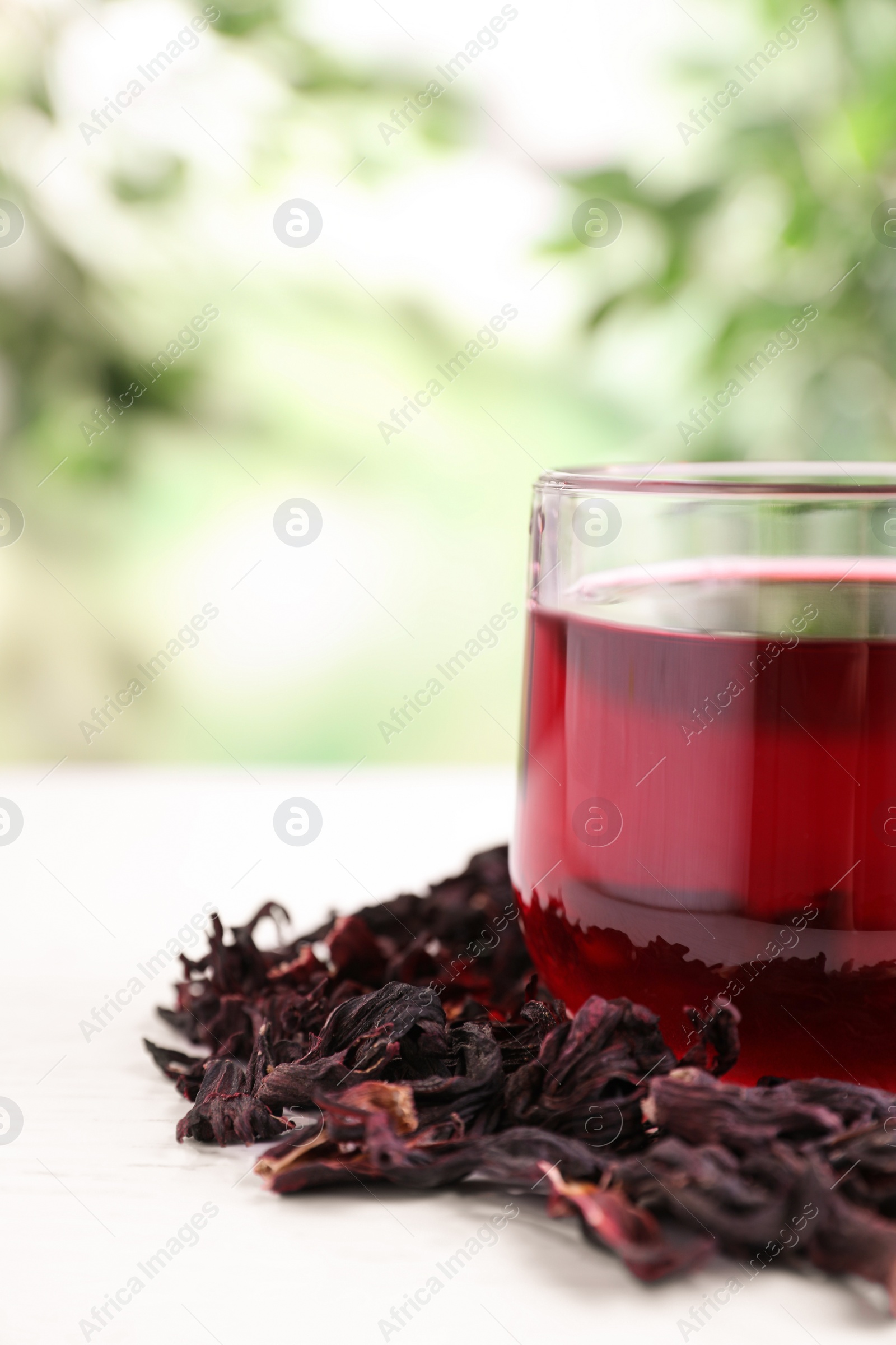 Photo of Fresh Hibiscus tea on white table against blurred background, closeup. Space for text