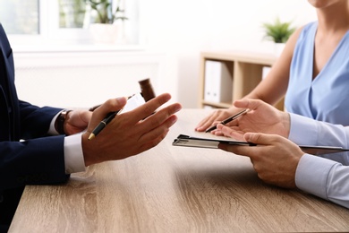 Photo of Lawyer working with clients at table in office, focus on hands