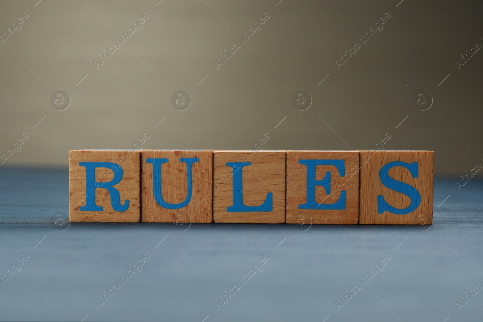 Photo of Word Rules made of cubes with letters on light blue wooden table