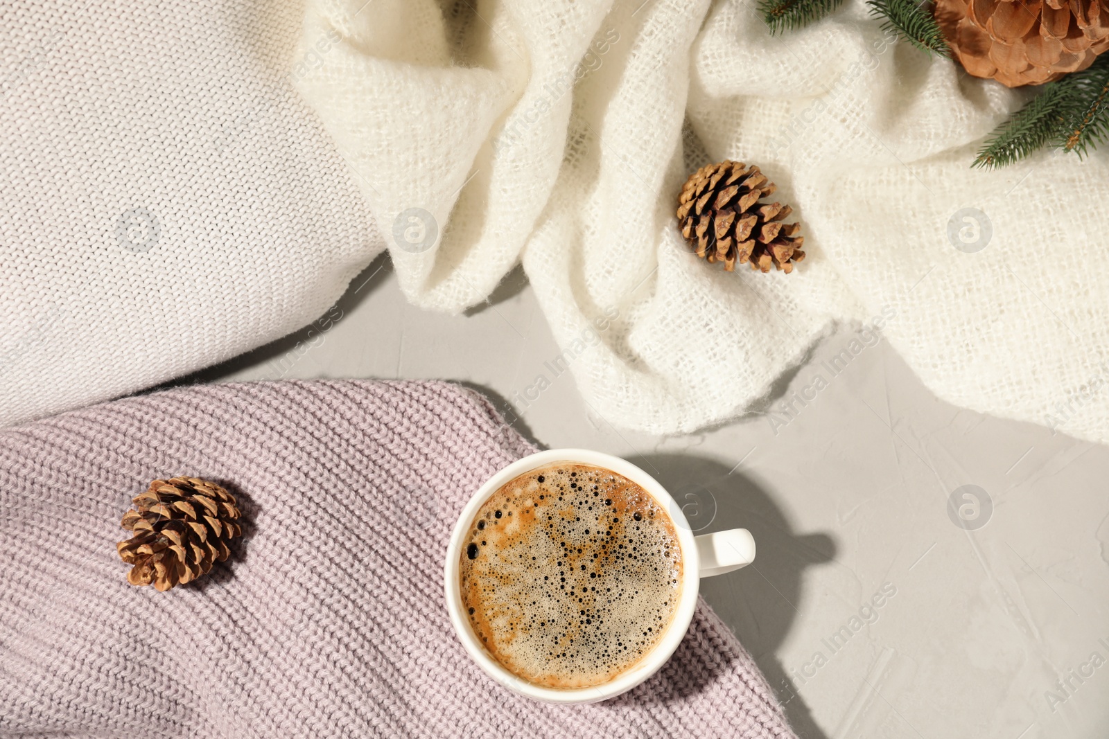 Photo of Flat lay composition with cup of coffee and clothes on light background. Winter drink