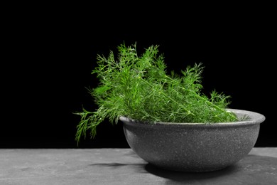 Photo of Fresh green dill in bowl on grey table, space for text