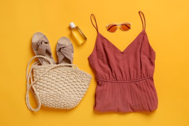 Flat lay composition with beach bag, clothes and other accessories on orange background