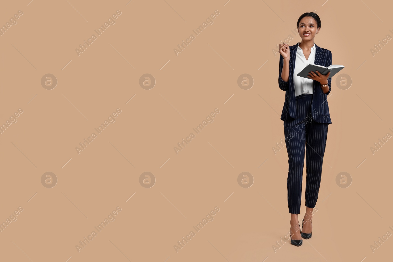 Photo of Beautiful secretary with notebook and pen on beige background, space for text