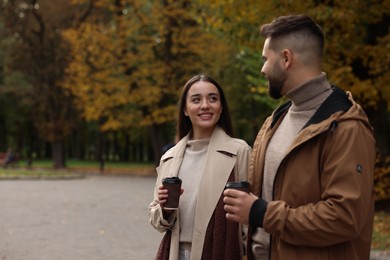 Romantic young couple spending time together in autumn park, space for text