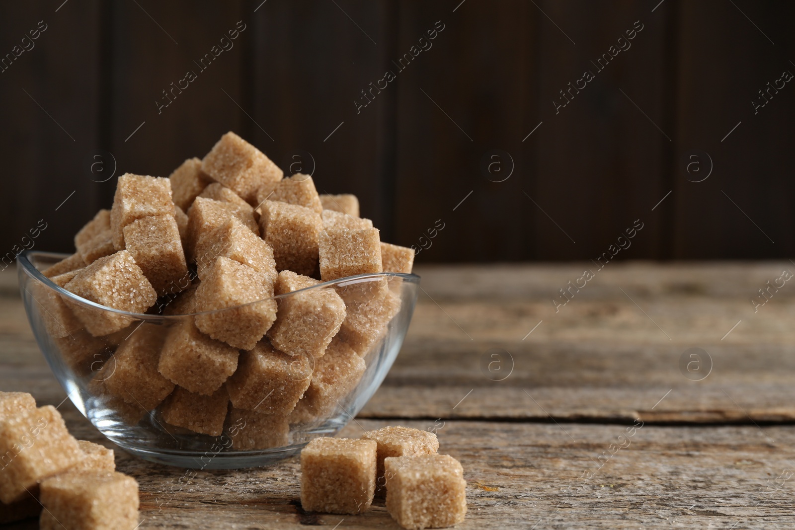 Photo of Brown sugar cubes on wooden table, closeup. Space for text