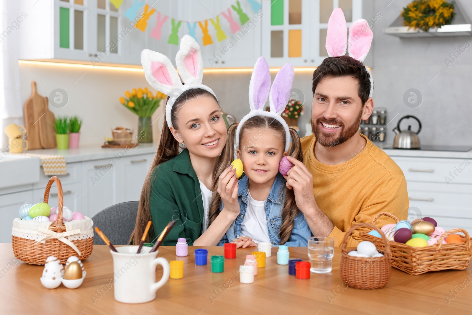 Photo of Happy family with Easter eggs at table in kitchen