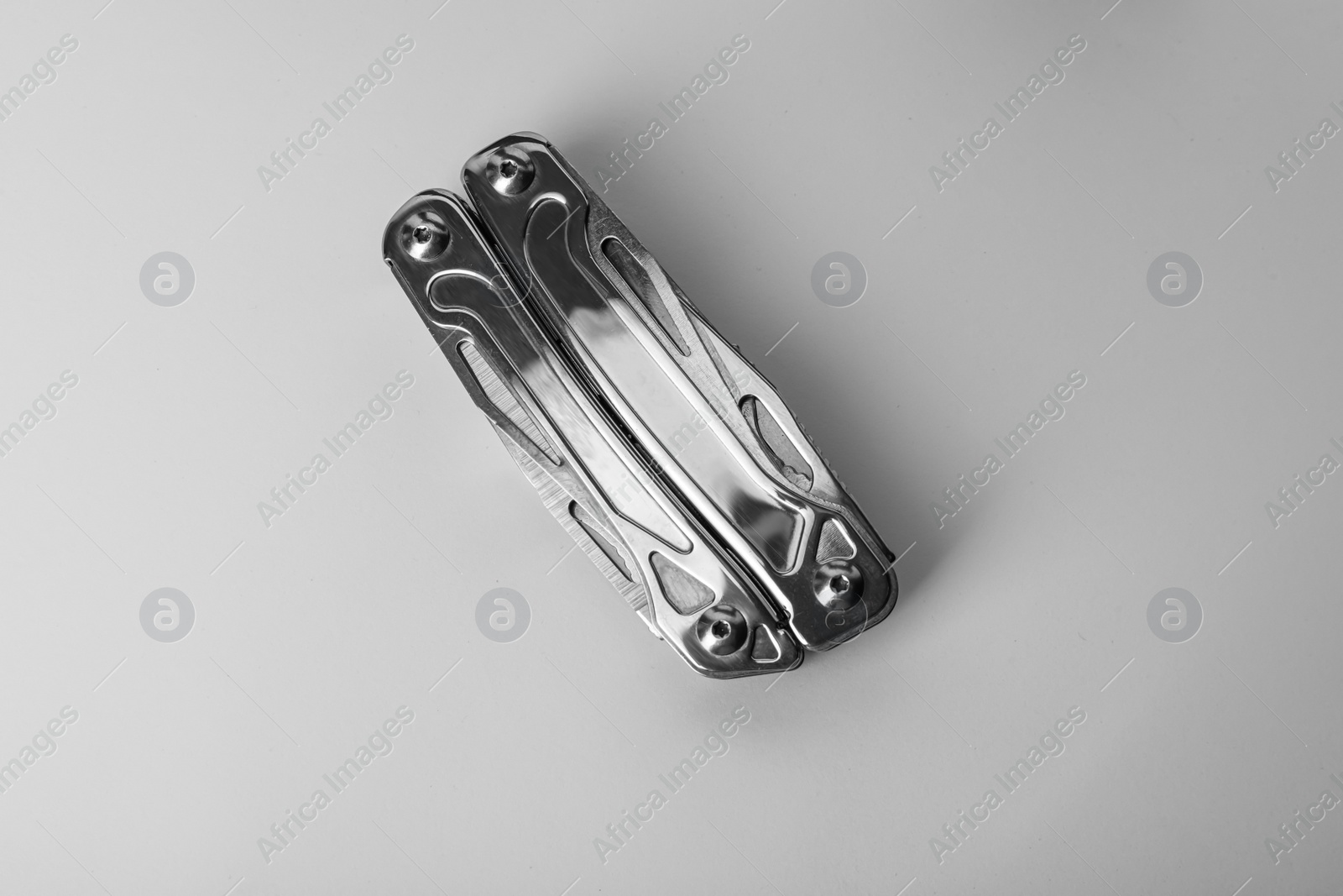 Photo of Compact portable metallic multitool on white background, top view
