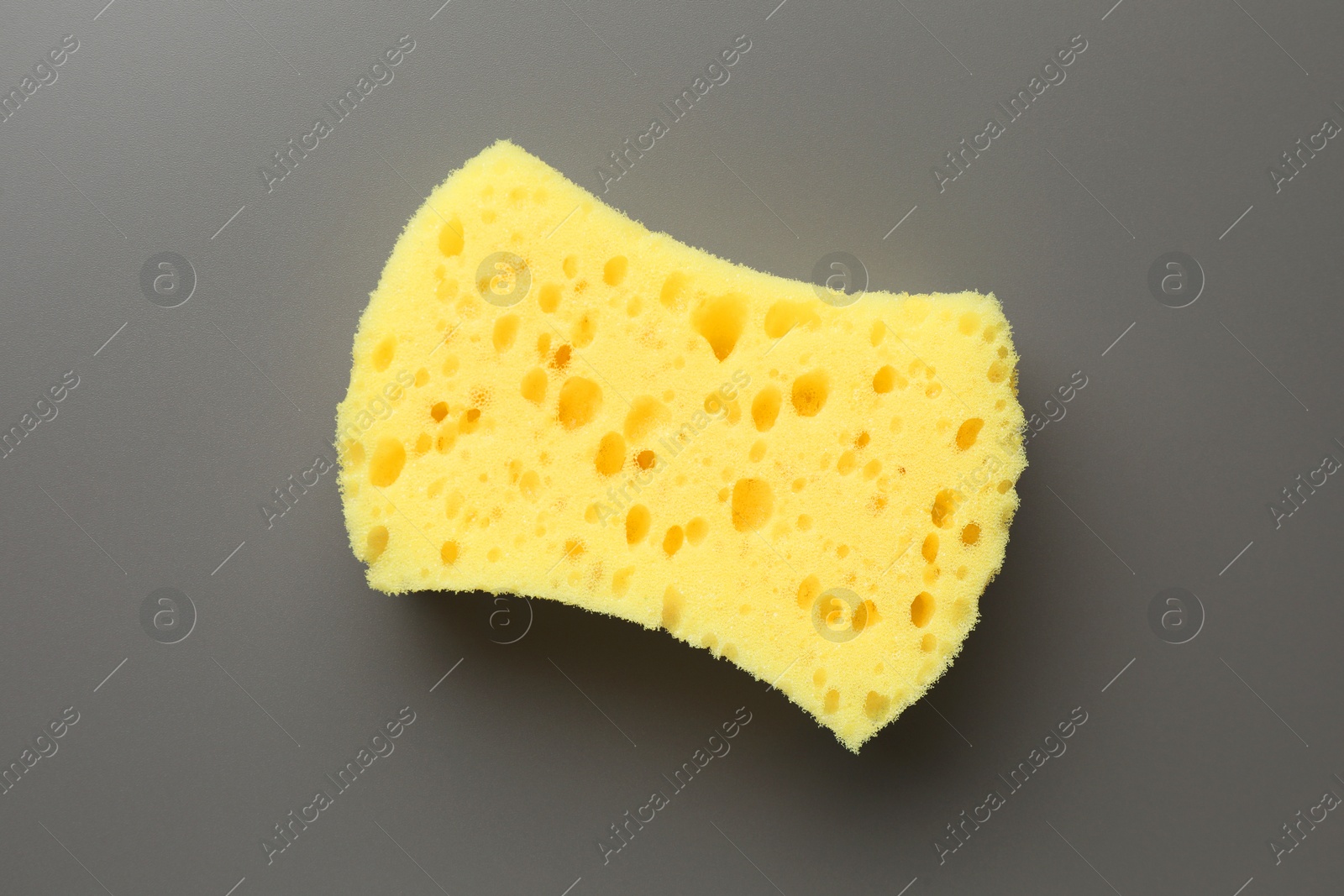 Photo of New yellow sponge on grey background, top view