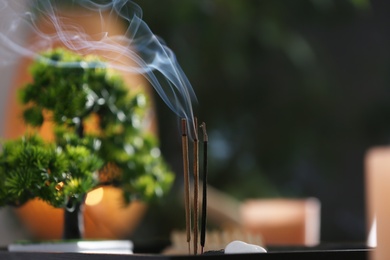 Miniature zen garden with smoldering incense sticks indoors, closeup