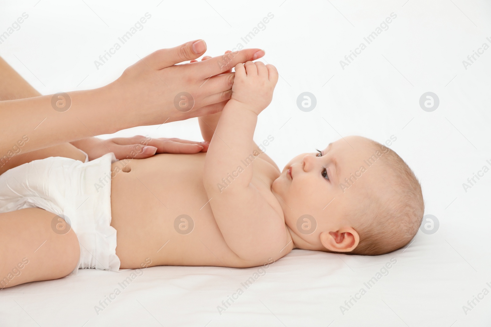 Photo of Mother and her cute child on white bed. Baby massage and exercises