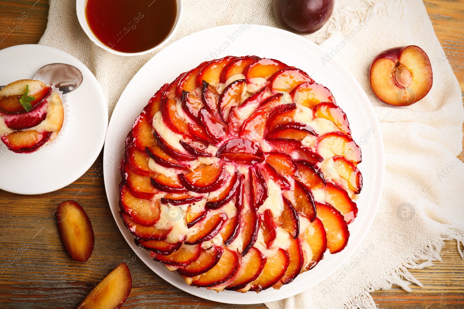 Photo of Delicious cake with plums on wooden table, flat lay