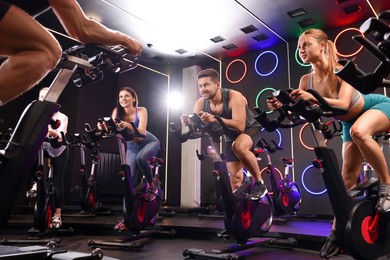 Group of people training on exercise bikes in fitness club