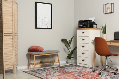 Stylish room interior with chest of drawers, modern printer and wooden table
