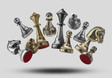 Different chess pieces falling on light grey background