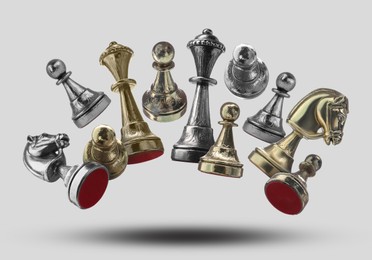 Image of Different chess pieces falling on light grey background