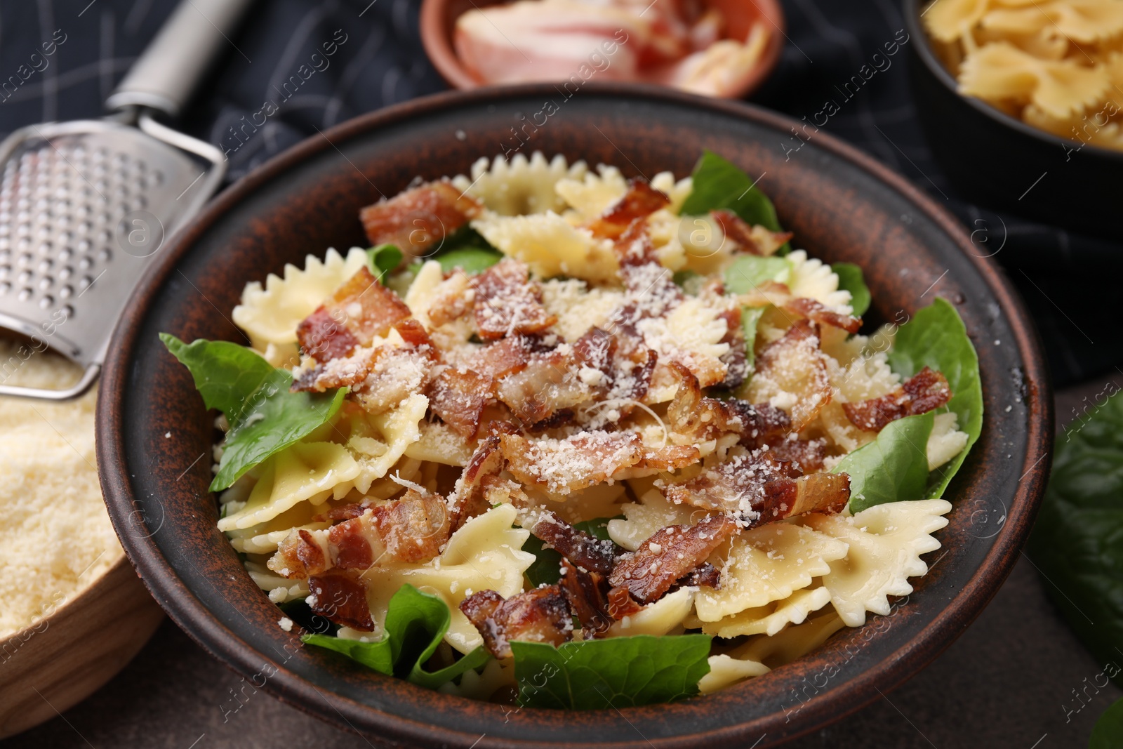 Photo of Tasty pasta with bacon and basil on brown table, closeup