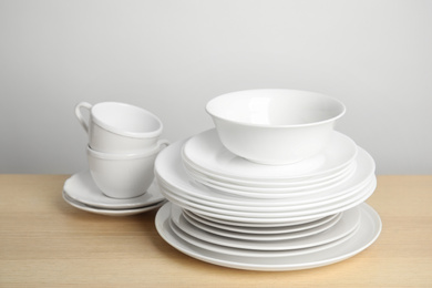 Clean plates, bowl and cups on wooden table against white background