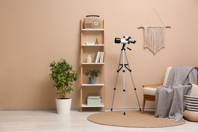 Tripod with modern telescope in stylish room