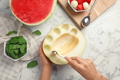 Photo of Woman making melon balls at table, top view