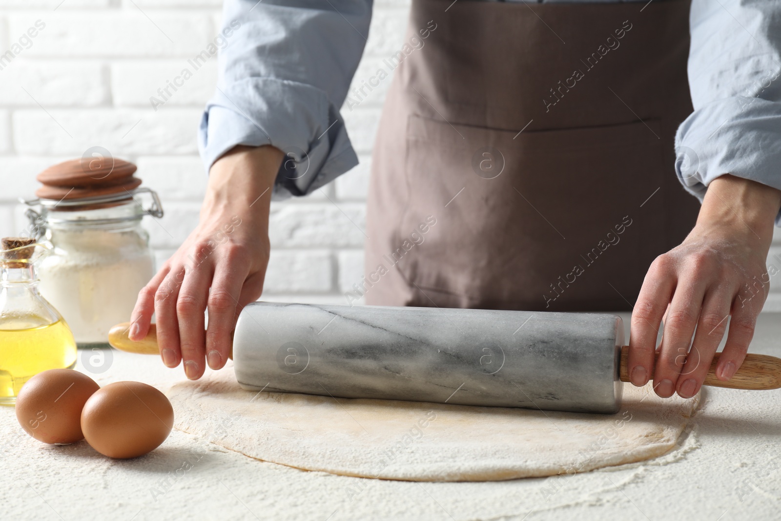 Photo of Woman rolling raw dough at table, closeup