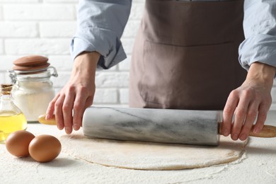 Photo of Woman rolling raw dough at table, closeup